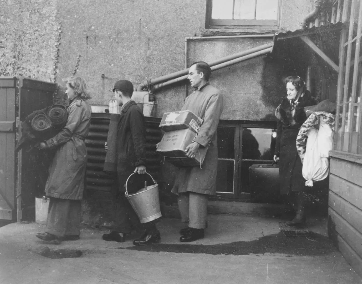 A photo from the National Archives showcasing several British residents lined up with their belongings to evacuate from Slapton Sands.