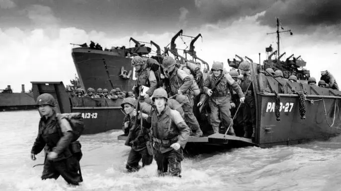A photo of several U.S. soldiers disembarking a WW2 era landing boat.