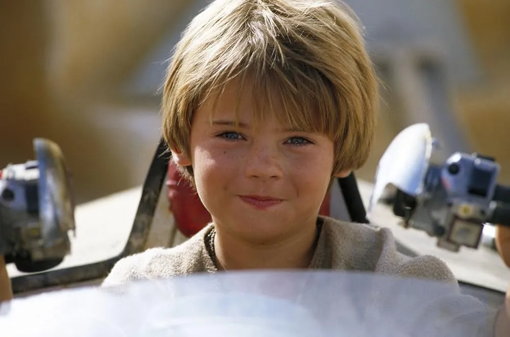 A still of young Anakin Skywalker, played by Jake Lloyd, podracing on Tatooine in The Phantom Menace.