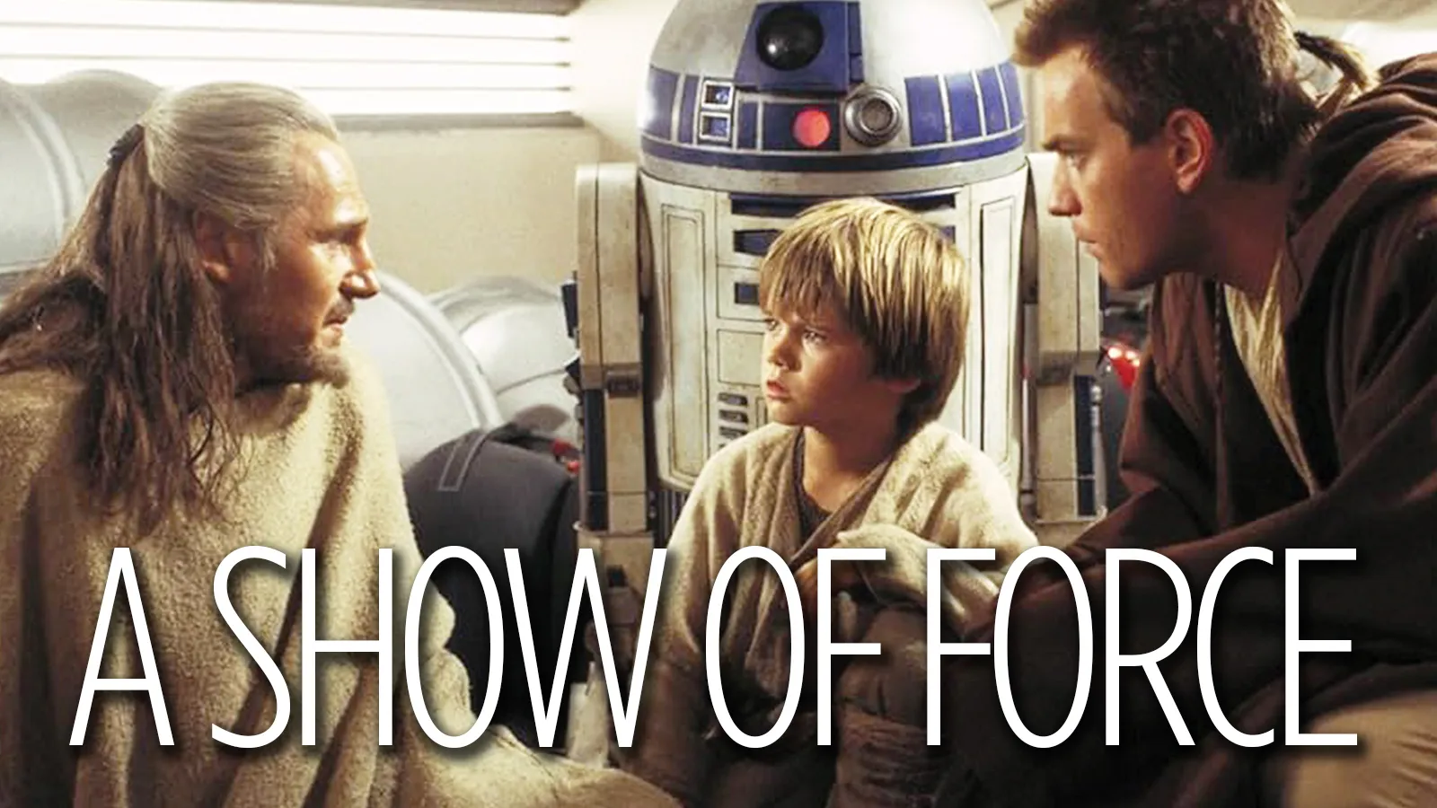 A still from The Phantom Menace showing Obi-Wan, played by Ewan Mcgregor, Qui-Gon Jinn, played by Liam Neeson, Anakin Skywalker, played by Jake Lloyd and R2D2 talking.