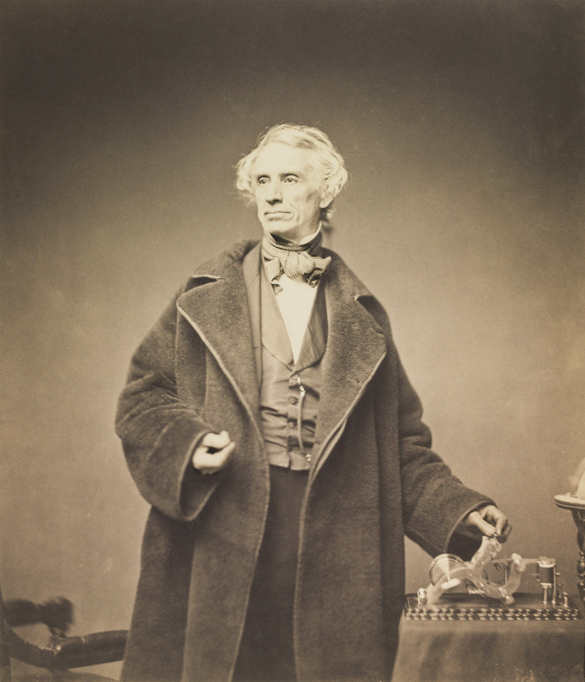 A portrait of Samuel Morse in a heavy coat with his telegraph.