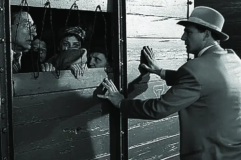 A still from the movie Schindler's List of Schindler with families in a train boxcar.